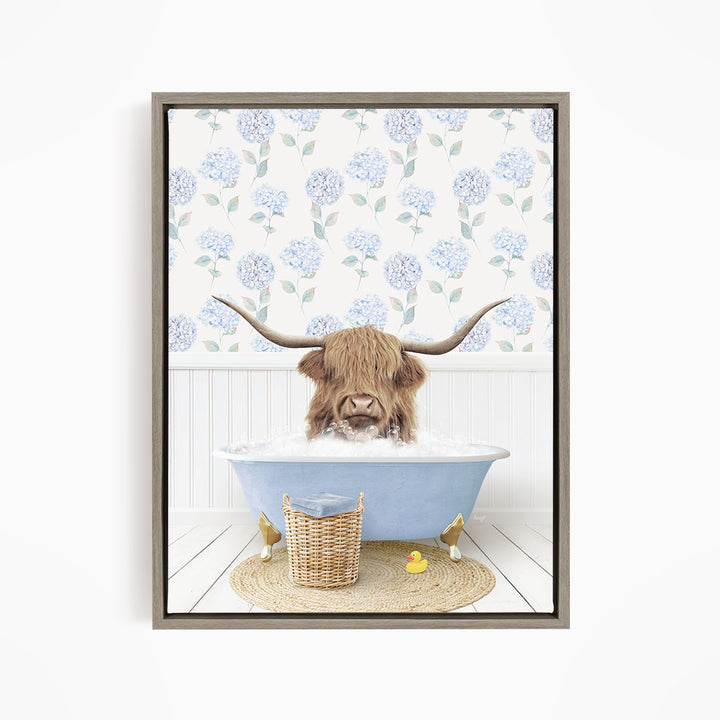 A brown cow with long horns is sitting in a blue bathtub filled with water, surrounded by a wicker basket and yellow rubber ducks.