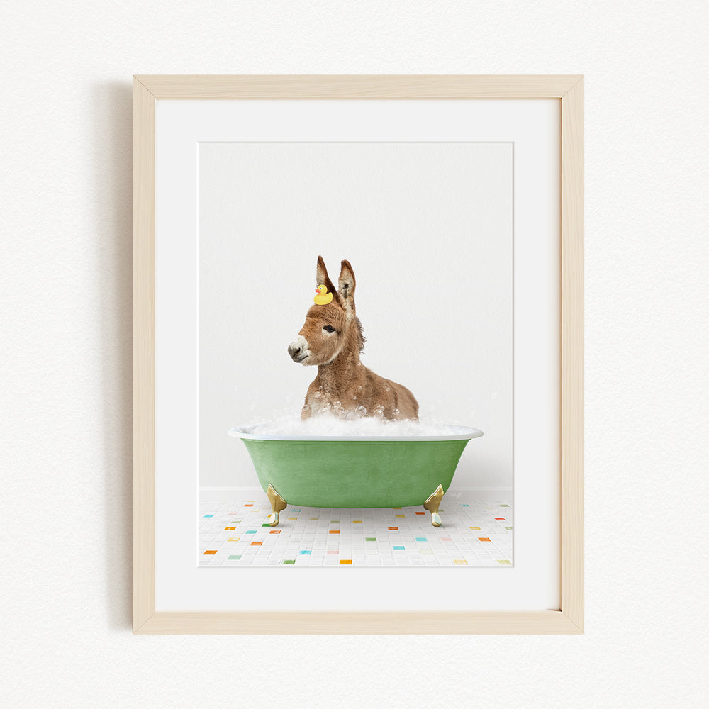 A donkey is sitting in a green bathtub filled with water, with a yellow object on its head.