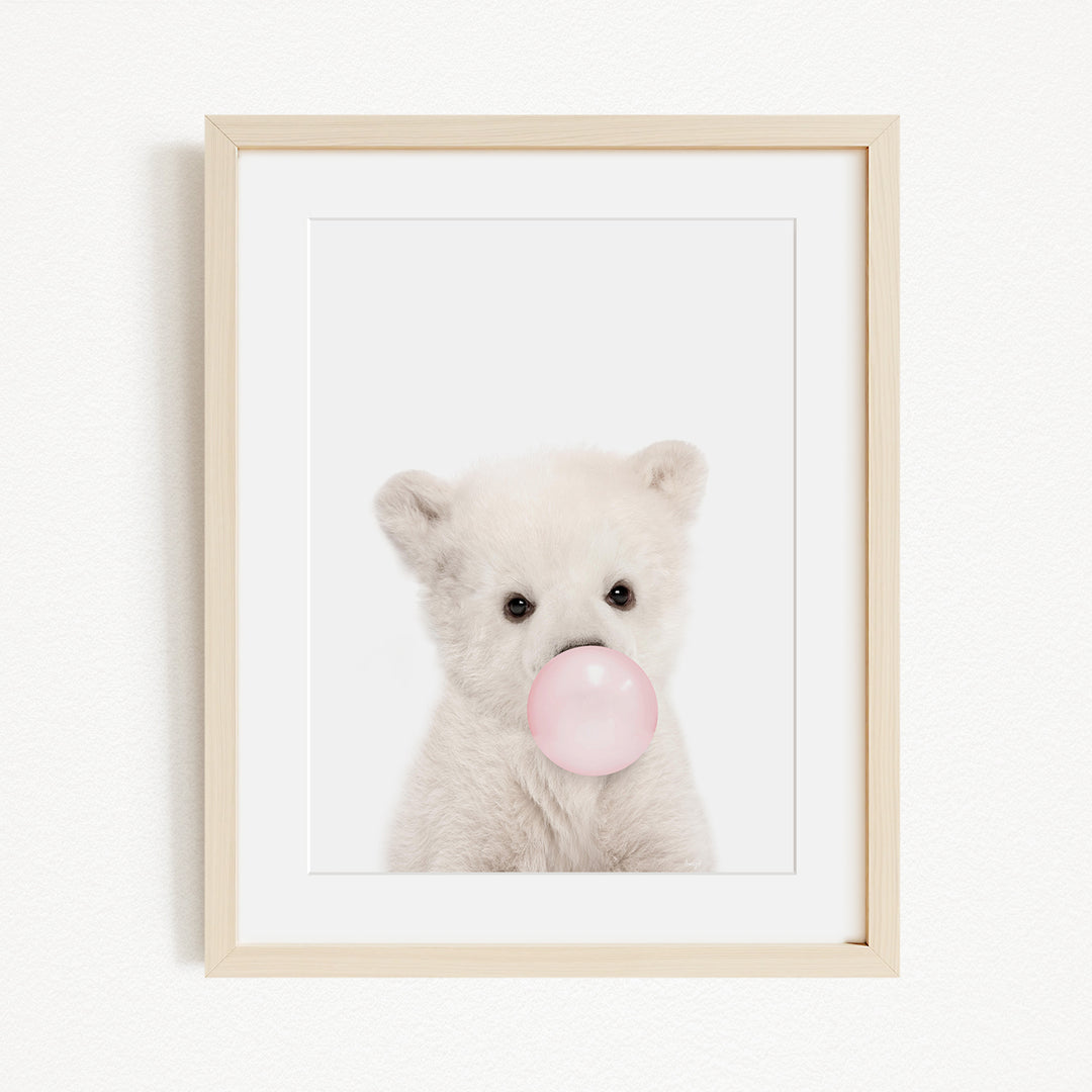 A cute white polar bear is blowing a bubble with a pink bubble gum bubble.