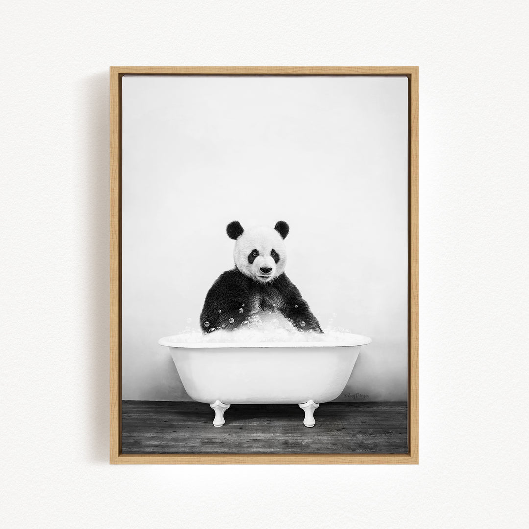 A panda bear sitting in a white bathtub filled with bubbles, looking directly at the camera.