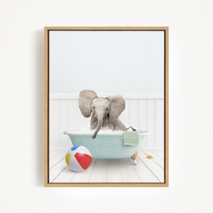 A baby elephant sitting in a bathtub filled with water, surrounded by a beach ball and a towel.