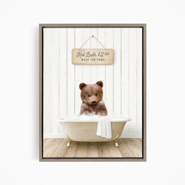 A brown bear sitting in a white bathtub, with a wooden sign above it that reads "Hot Bath $2.00 WASH YOUR Paws".