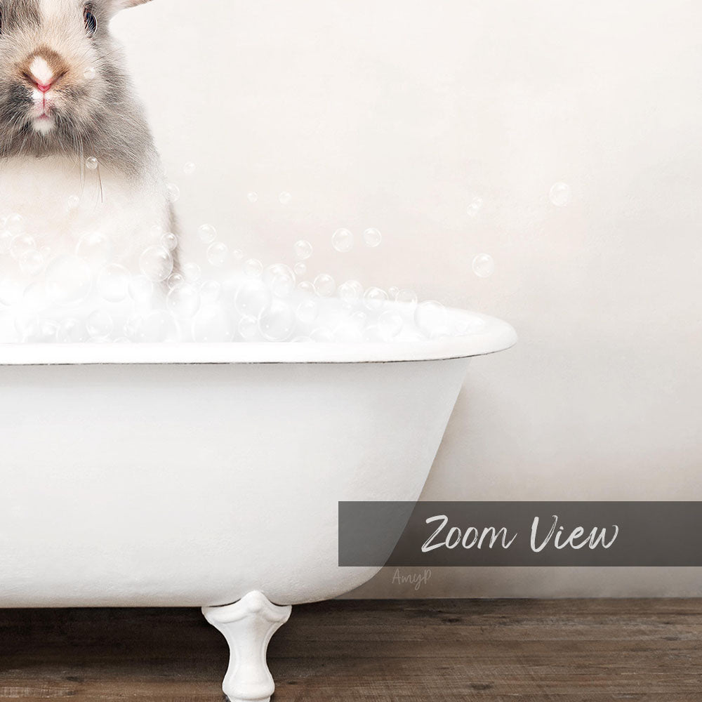 A fluffy white rabbit sitting in a white bathtub filled with bubbles, with the text "Zoom View" displayed below the image.