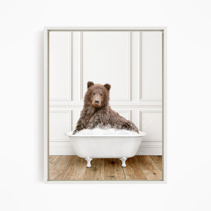 A brown bear sitting in a white bathtub filled with water, looking directly at the camera.