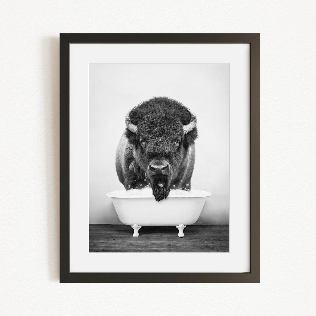 A black and white photograph of a buffalo standing in a bathtub.