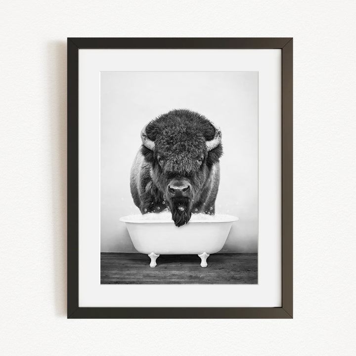 A black and white photograph of a buffalo standing in a bathtub.