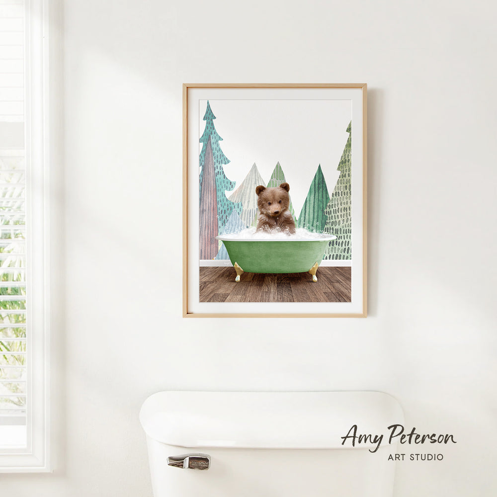 A framed print of a teddy bear sitting in a green bathtub, surrounded by a winter landscape with pine trees.