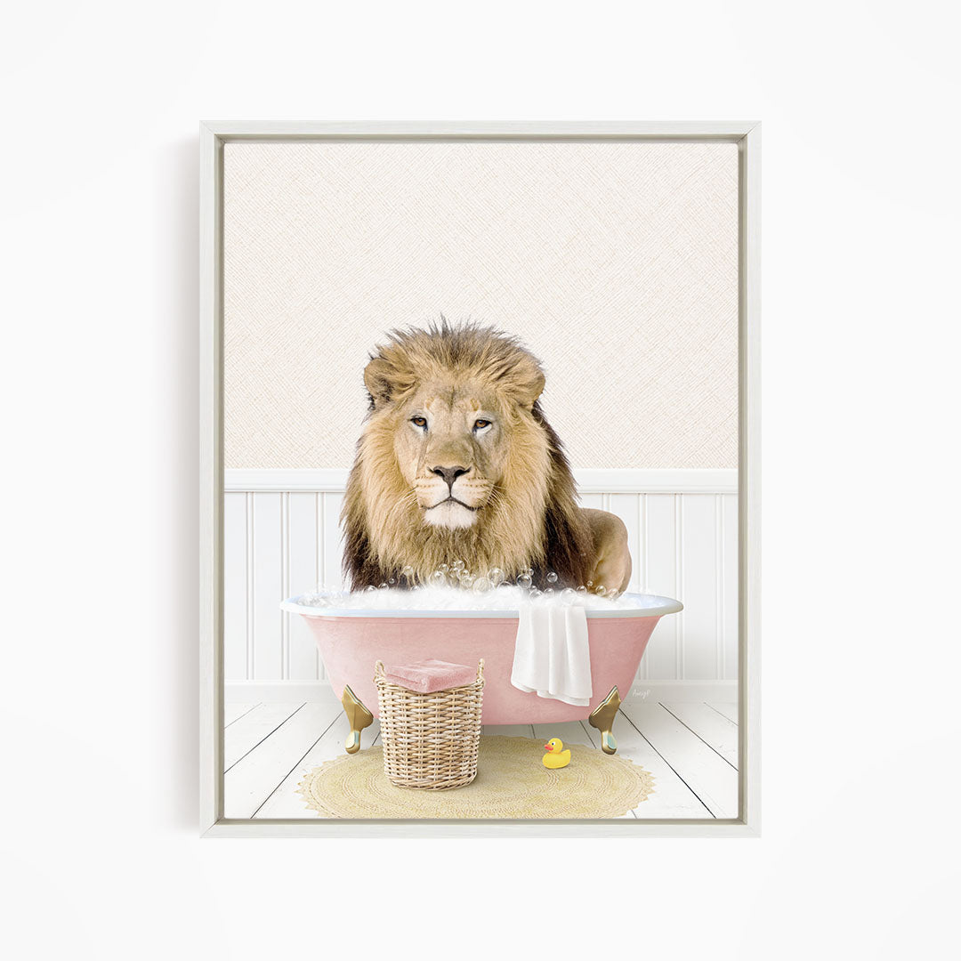 A lion sitting in a pink bathtub filled with bubbles, surrounded by a yellow rubber duck and a white towel.