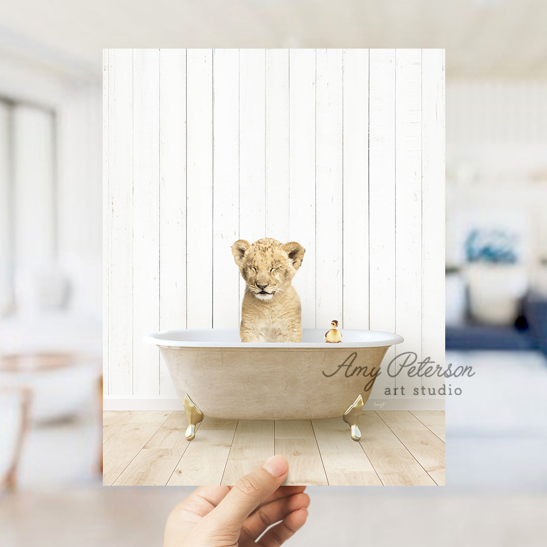 a hand holding a photo of a baby lion in a bathtub