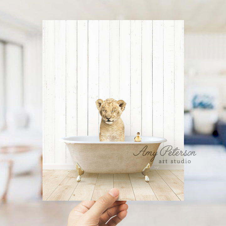 a hand holding a photo of a baby lion in a bathtub