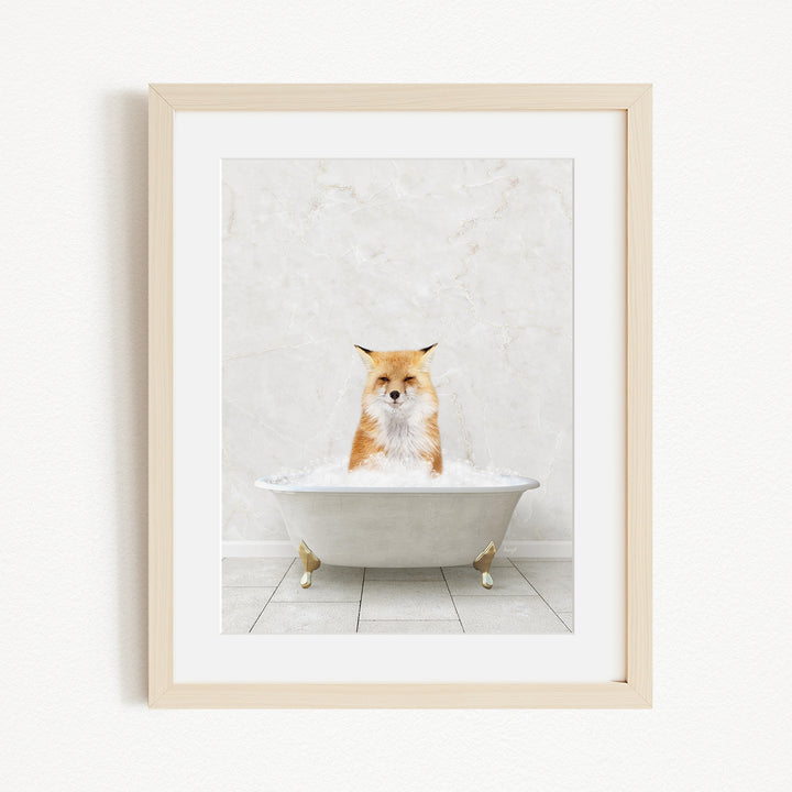 A red fox is sitting in a white bathtub filled with bubbles, looking directly at the camera.