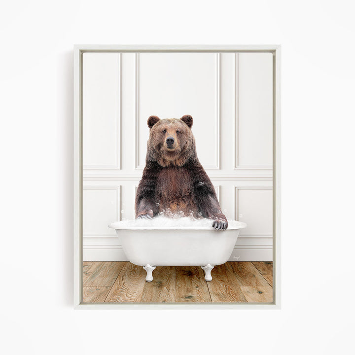 A brown bear sitting in a white bathtub filled with water, appearing to enjoy the bath.
