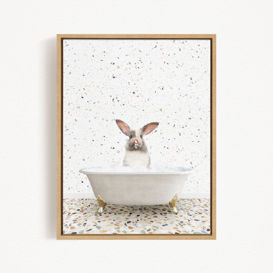 A white rabbit sitting in a white bathtub filled with water, surrounded by a speckled tiled floor.