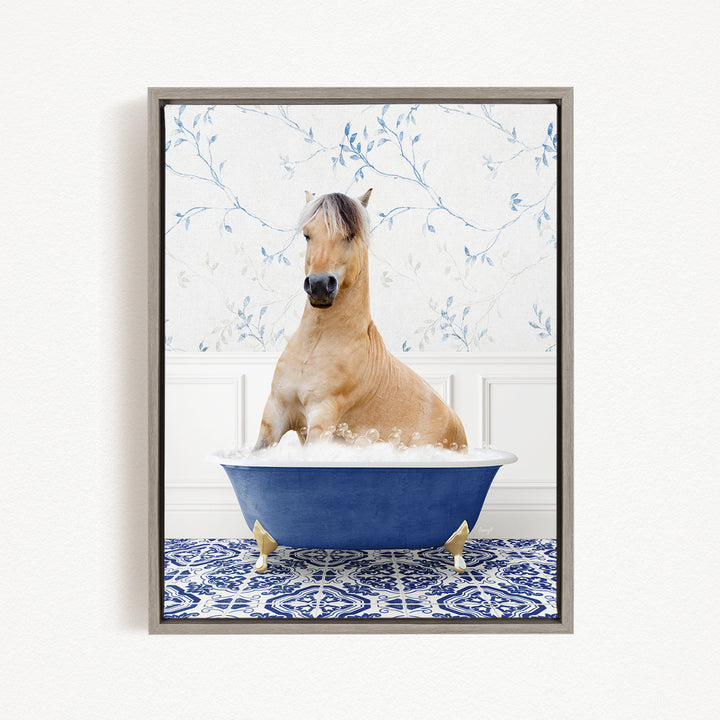 A light brown horse is sitting in a blue bathtub filled with water, surrounded by a patterned blue and white rug.
