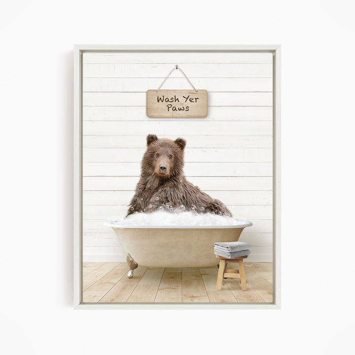 A brown bear sitting in a bathtub filled with water, with a sign above that says "Wash Your Paws".
