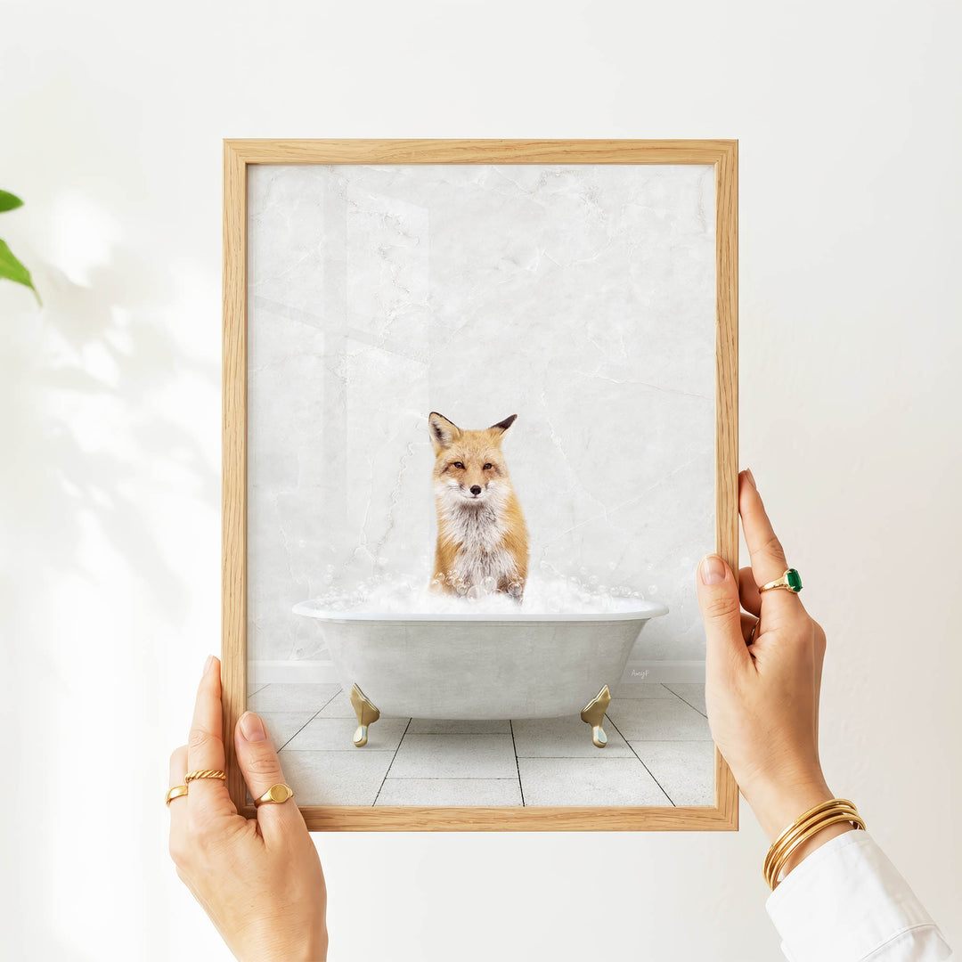 A person's hands are holding a framed picture of a cat sitting in a bathtub filled with water.