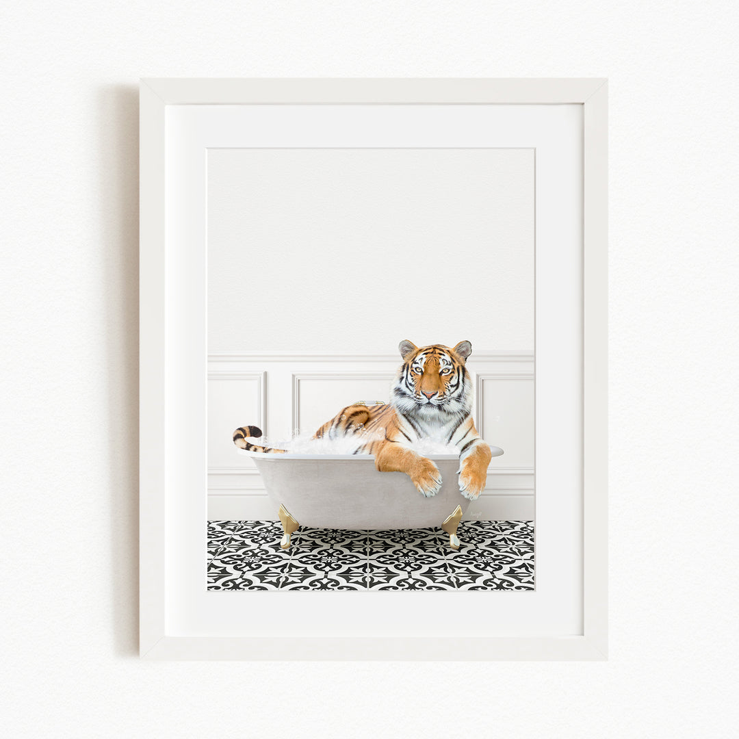 A tiger is sitting in a white bathtub filled with bubbles, resting on a black and white patterned floor.