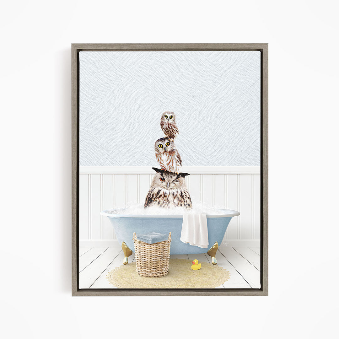 A framed image depicting a group of owls sitting in a bathtub, with one owl sitting on top of the others.