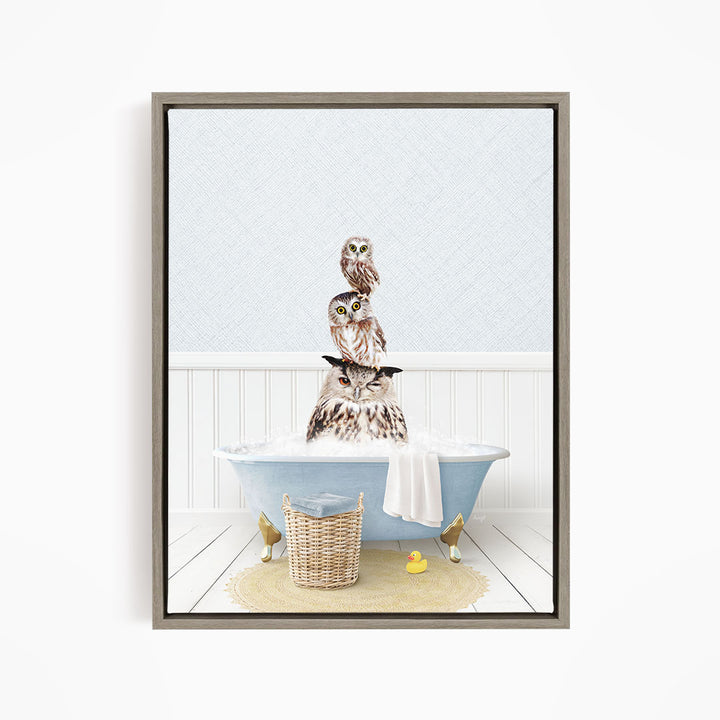 A framed image depicting a group of owls sitting in a bathtub, with one owl sitting on top of the others.