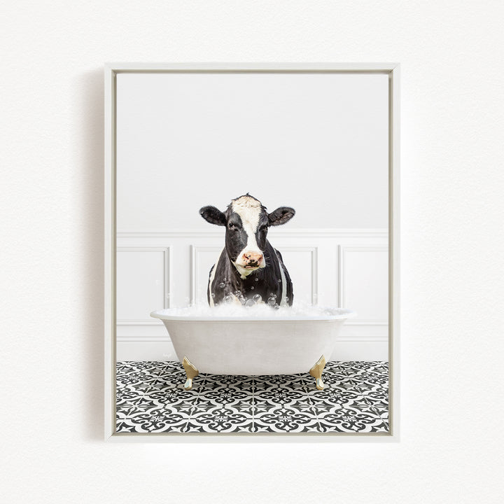 A black and white cow is sitting in a white bathtub filled with water, creating a whimsical and humorous scene.