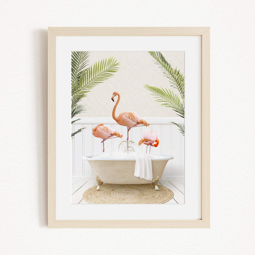A framed image depicting three pink flamingos standing in a bathtub filled with water, surrounded by green palm leaves.