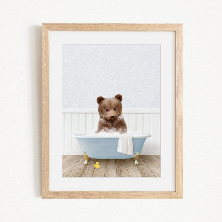 A cute brown bear sitting in a blue bathtub filled with bubbles, surrounded by yellow rubber duckies.