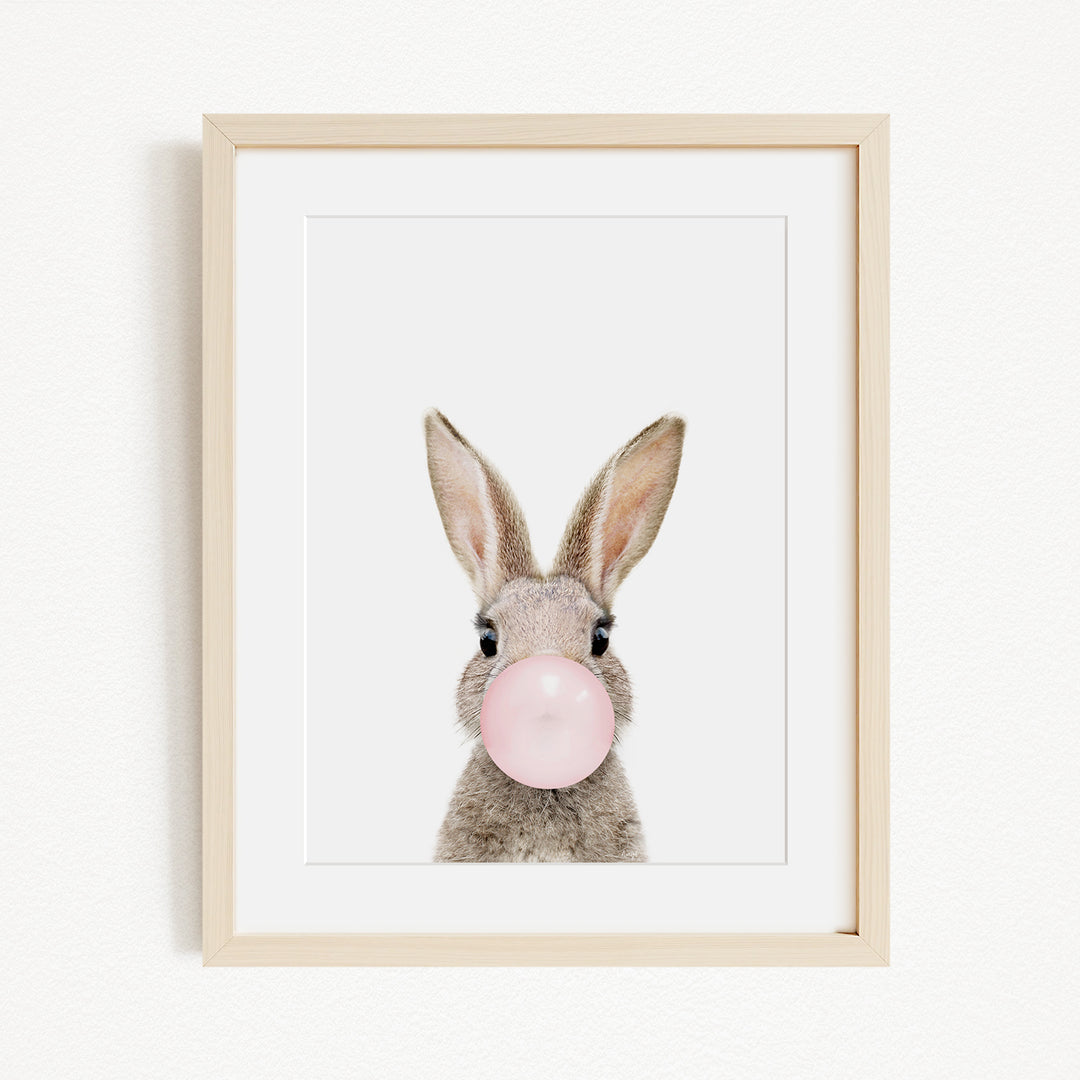 A framed image of a rabbit blowing a bubble with a pink bubblegum bubble.