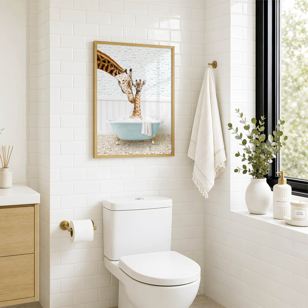 A bathroom with a white toilet, a framed picture of two giraffes in a bathtub, and a window with greenery on the sill.