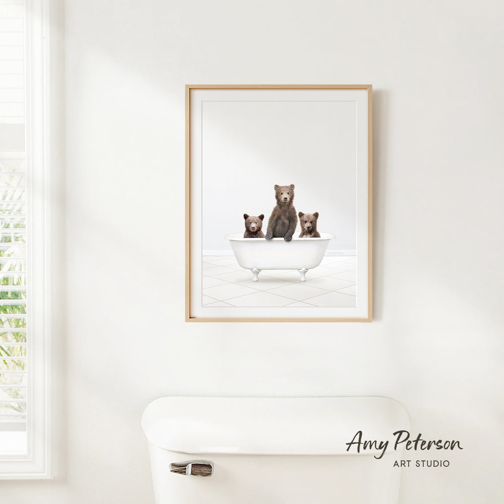 A framed image of three bears sitting in a bathtub, with the bears appearing to be brown and black in color.
