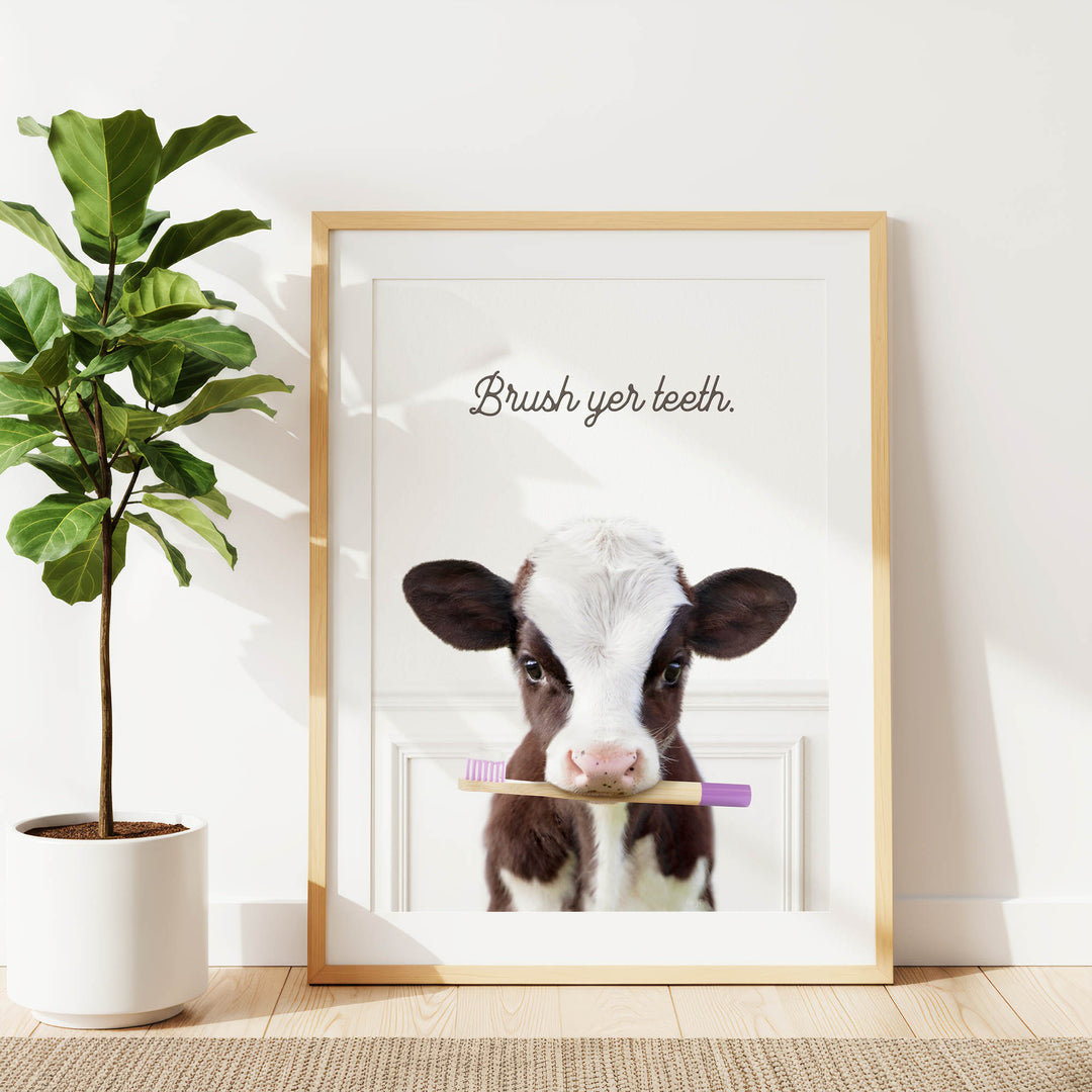 A framed image of a cow holding a toothbrush, with the text "Brush yer teeth."
