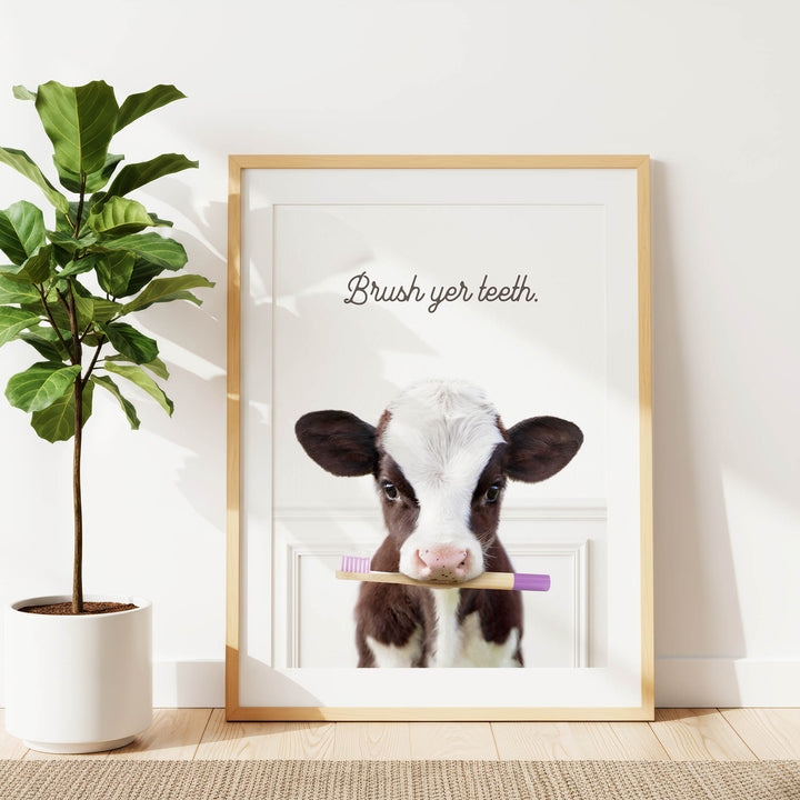 A framed image of a cow holding a toothbrush, with the text "Brush yer teeth."