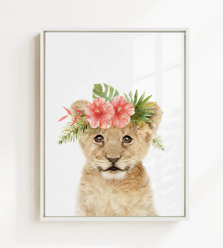 A young lion cub wearing a floral crown of pink flowers and green leaves.