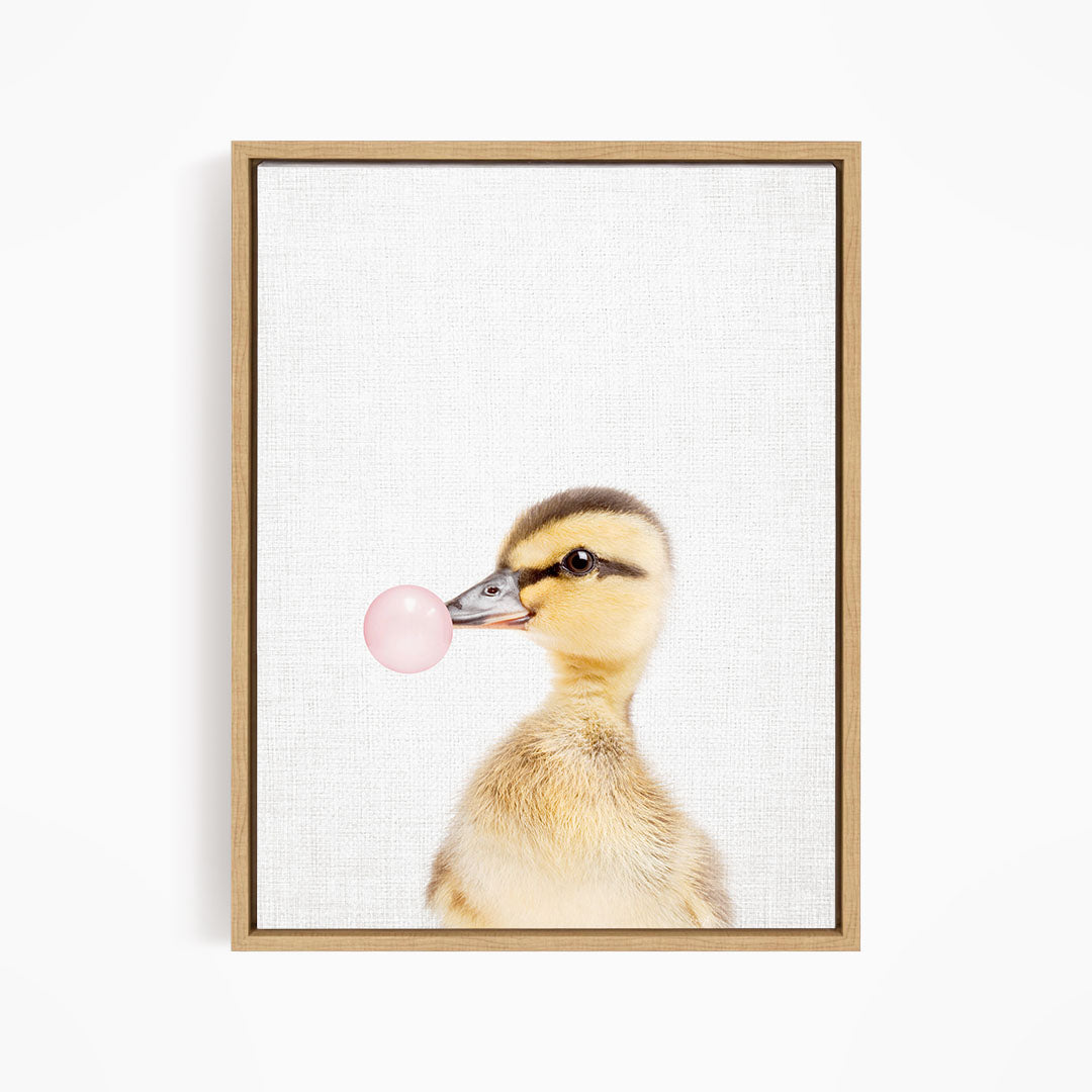 A cute duckling blowing a bubble with a pink bubble gum bubble.