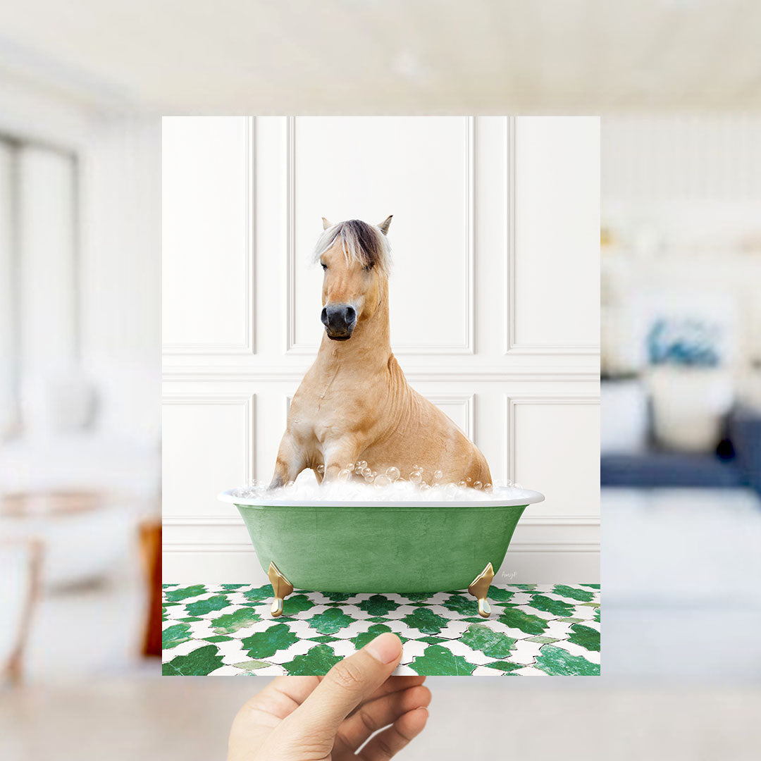 A light brown horse sitting in a green bathtub filled with bubbles, with a hand holding the image up to the viewer.