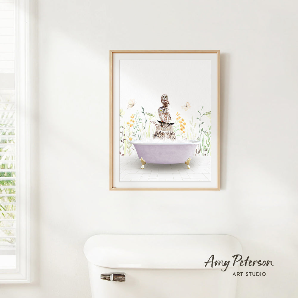 A framed print of a woman sitting in a bathtub surrounded by flowers and butterflies is hanging on a white wall.