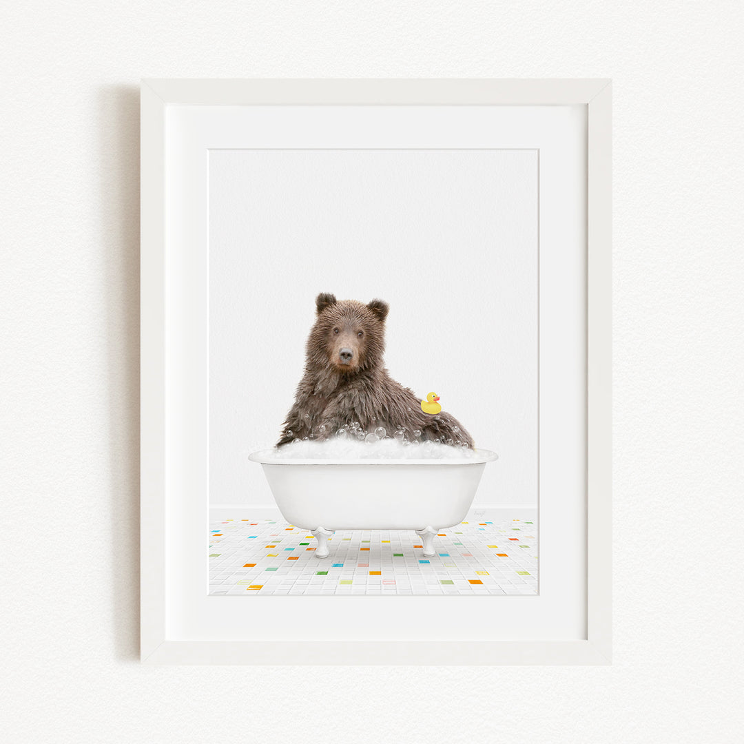 A brown bear sitting in a white bathtub filled with bubbles, with a yellow rubber duck floating nearby.