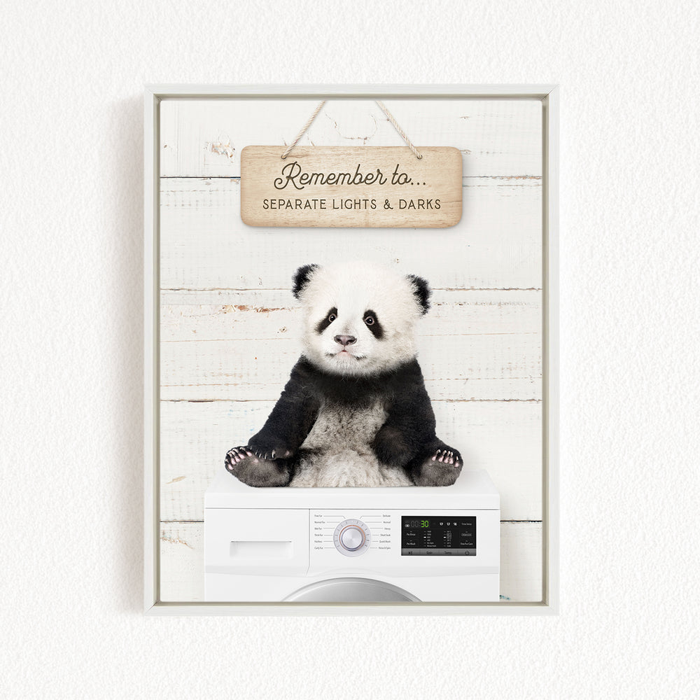 A panda bear sitting on top of a washing machine, with a wooden sign above that says "Remember to separate lights & darks".