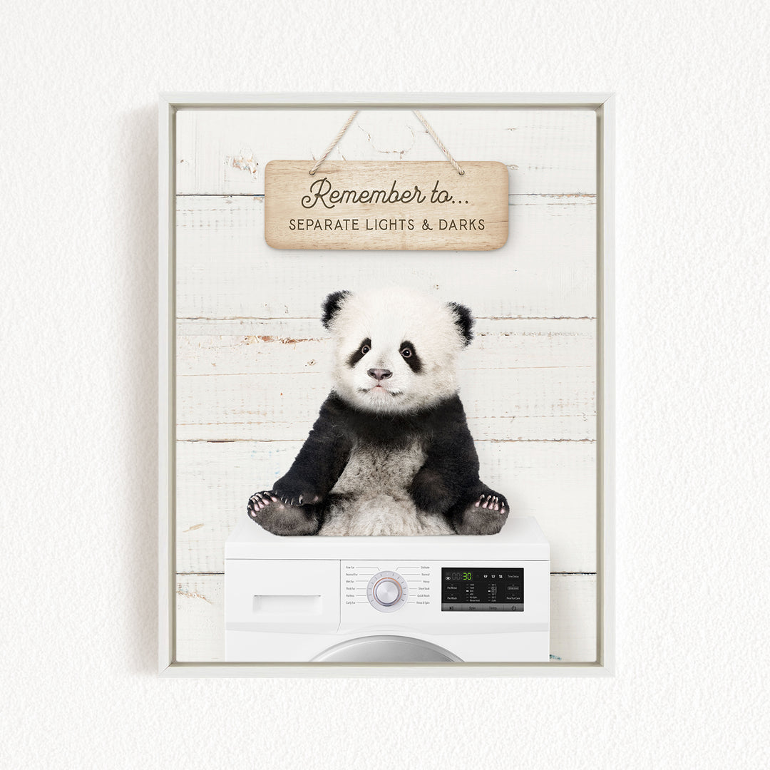 A panda bear sitting on top of a washing machine, with a wooden sign above that says "Remember to separate lights & darks".