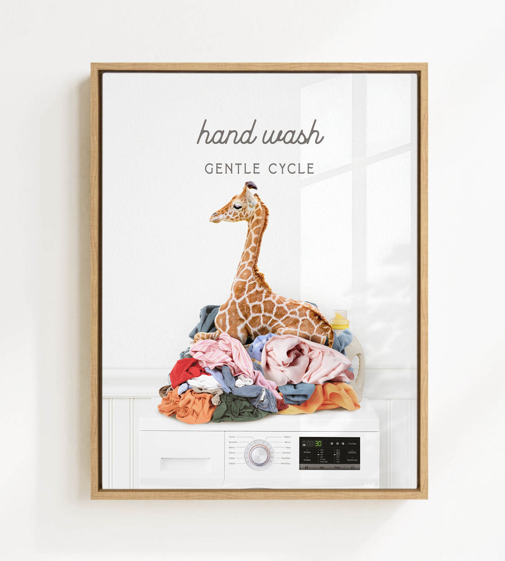 A giraffe sitting on a pile of laundry in a room with a washing machine.