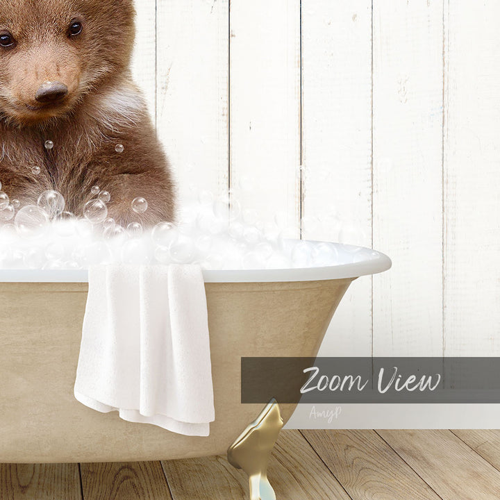 A brown bear sitting in a bathtub filled with bubbles, with a towel draped over the side and a "Zoom View" label below the image.