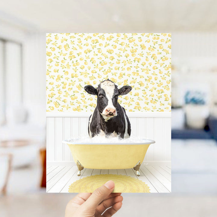 A black and white cow is sitting in a yellow bathtub filled with water, surrounded by a yellow and white patterned wall.