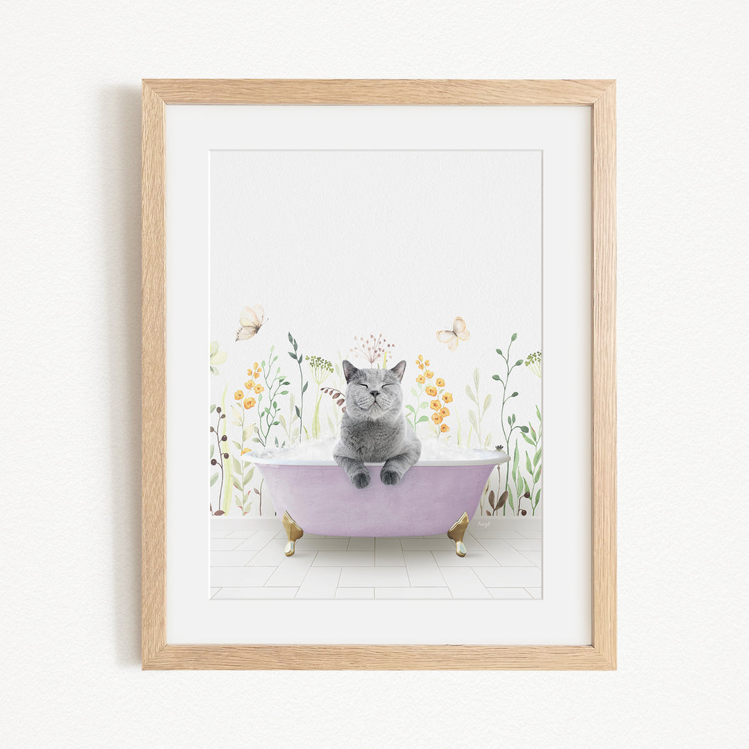 A gray cat sitting in a purple bathtub, surrounded by flowers and butterflies, in a framed artwork.