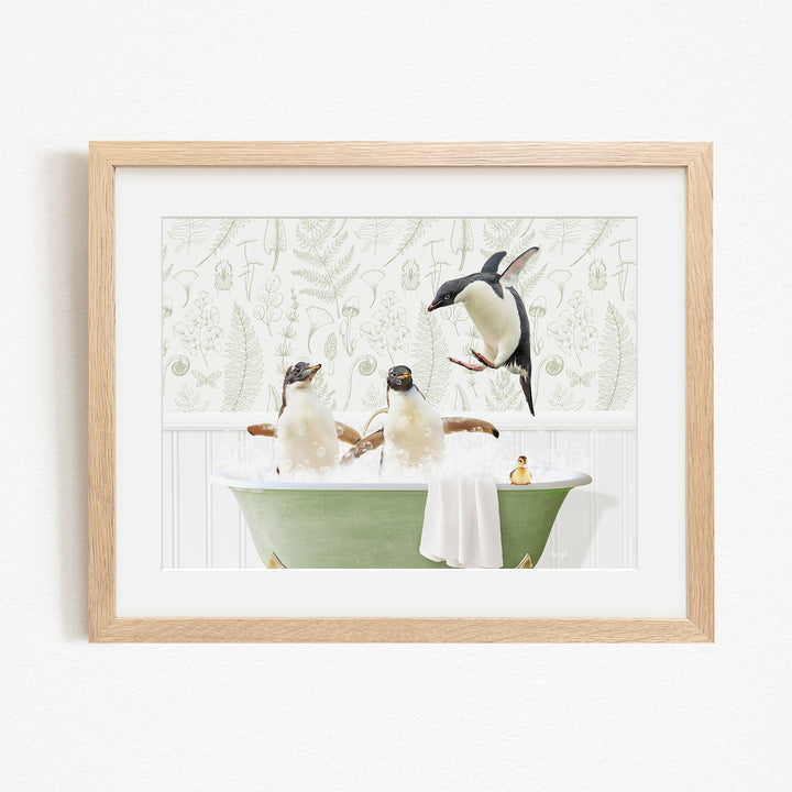 A framed image depicting three penguins sitting in a green bathtub, with one penguin flying towards the others.