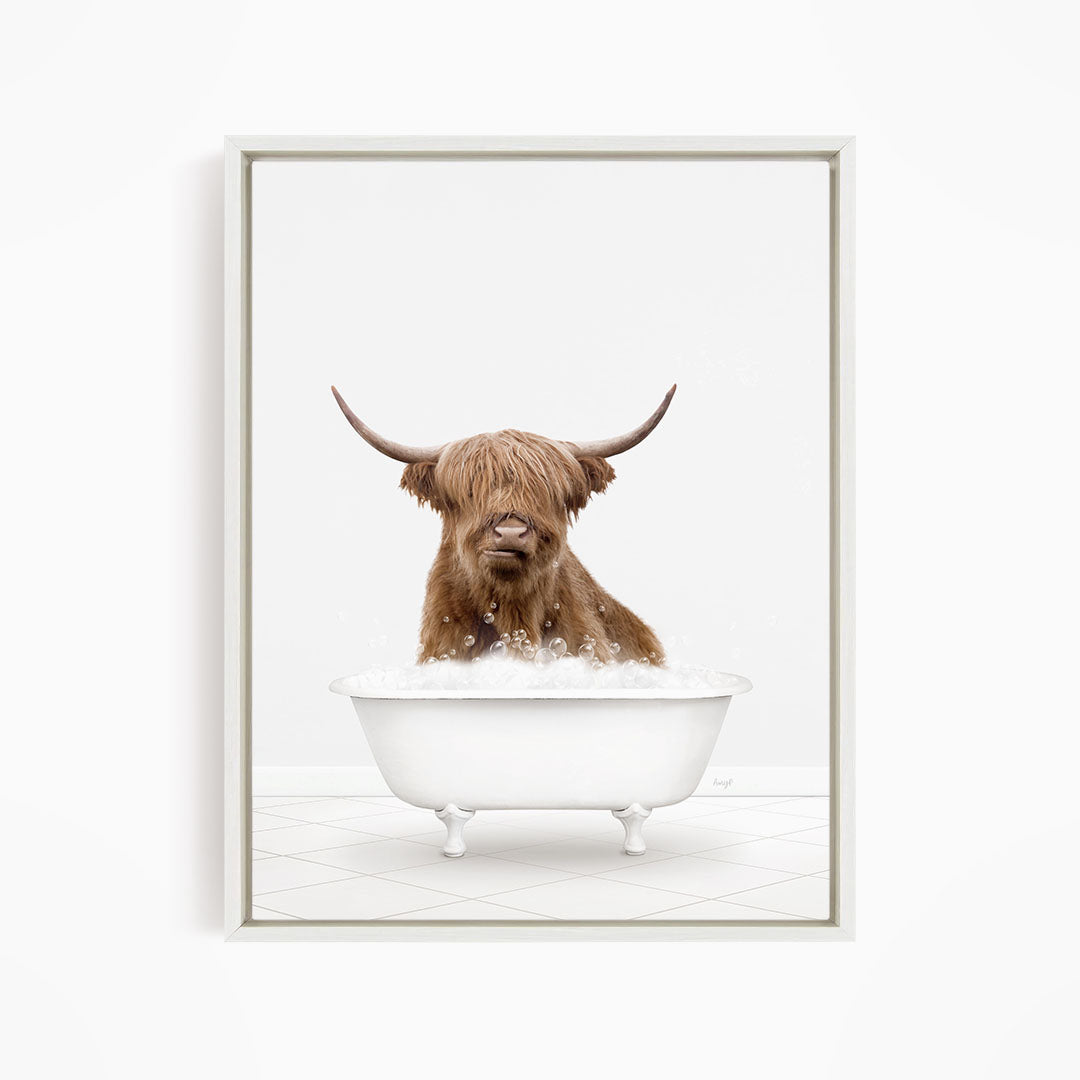 A brown cow with long horns is sitting in a white bathtub filled with water, appearing to enjoy the bath.