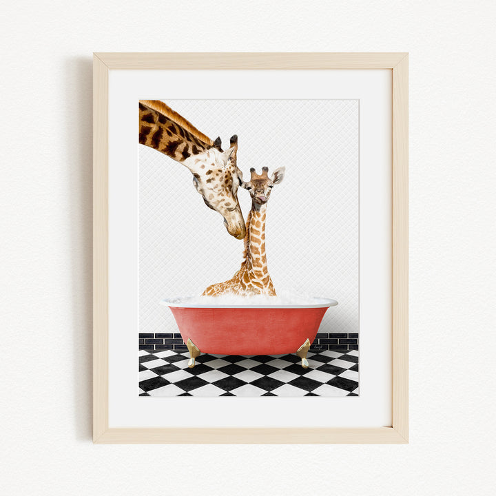 A mother giraffe and her baby giraffe are sitting together in a red bathtub, with the mother gently licking her baby.
