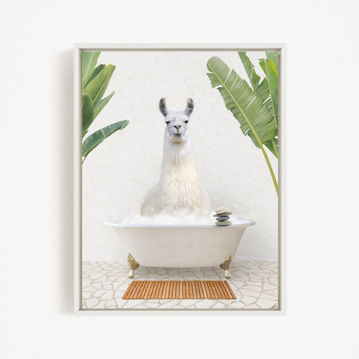 A white llama sitting in a white bathtub filled with bubbles, surrounded by green leaves and a wooden mat on the floor.