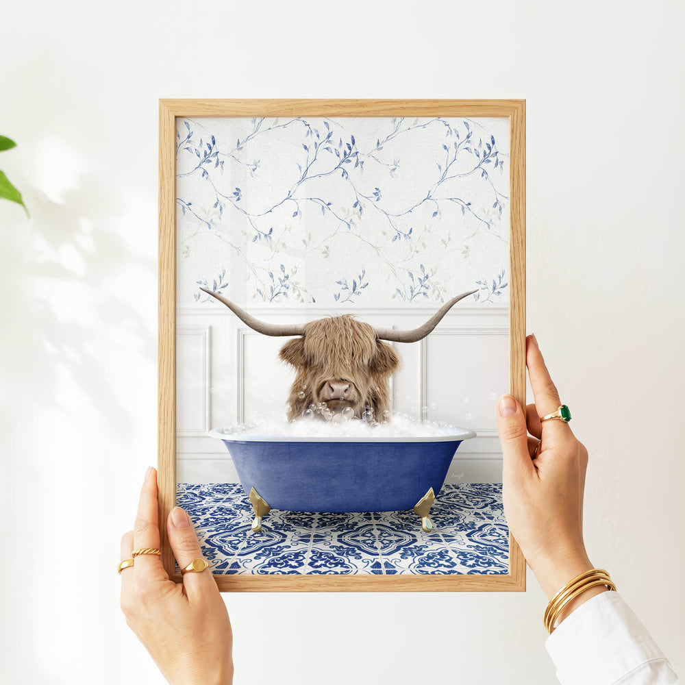A person's hands are holding a framed image of a horned animal, likely a yak or a yak, sitting in a blue bathtub filled with water.