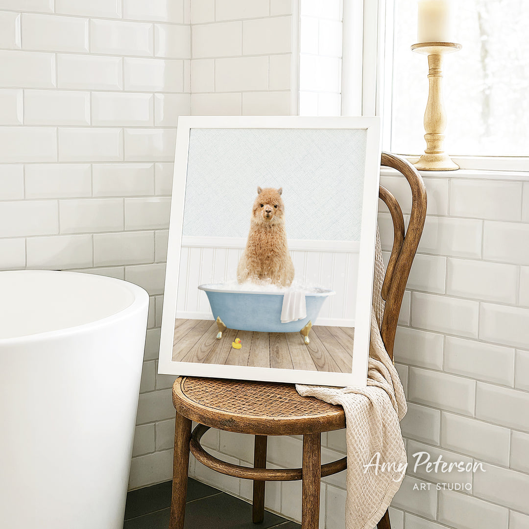 A framed image of a small brown dog sitting in a blue bathtub, surrounded by white tiles, is displayed on a wooden chair in a bathroom setting.