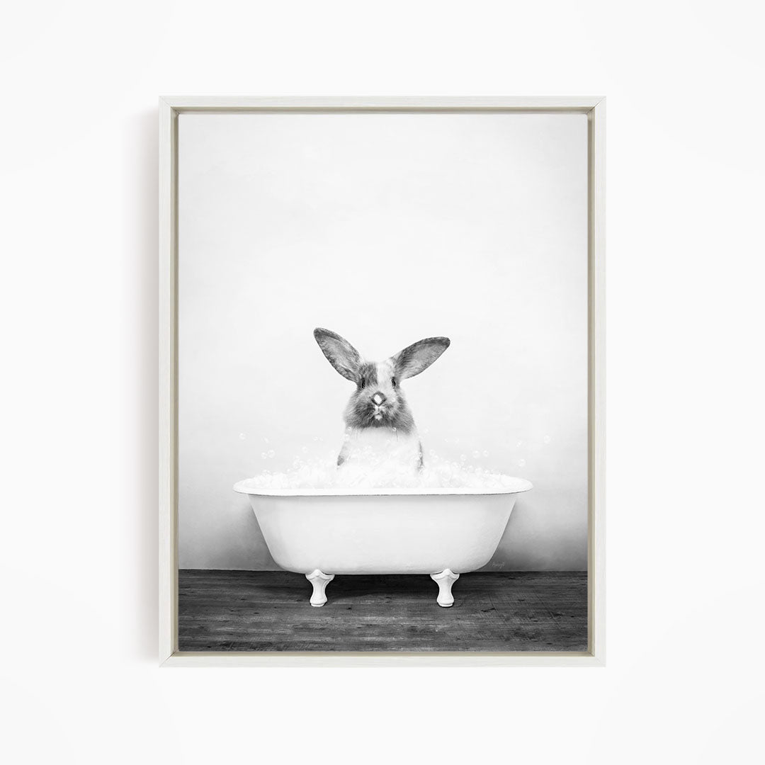 A rabbit sitting in a white bathtub filled with water, looking directly at the camera.