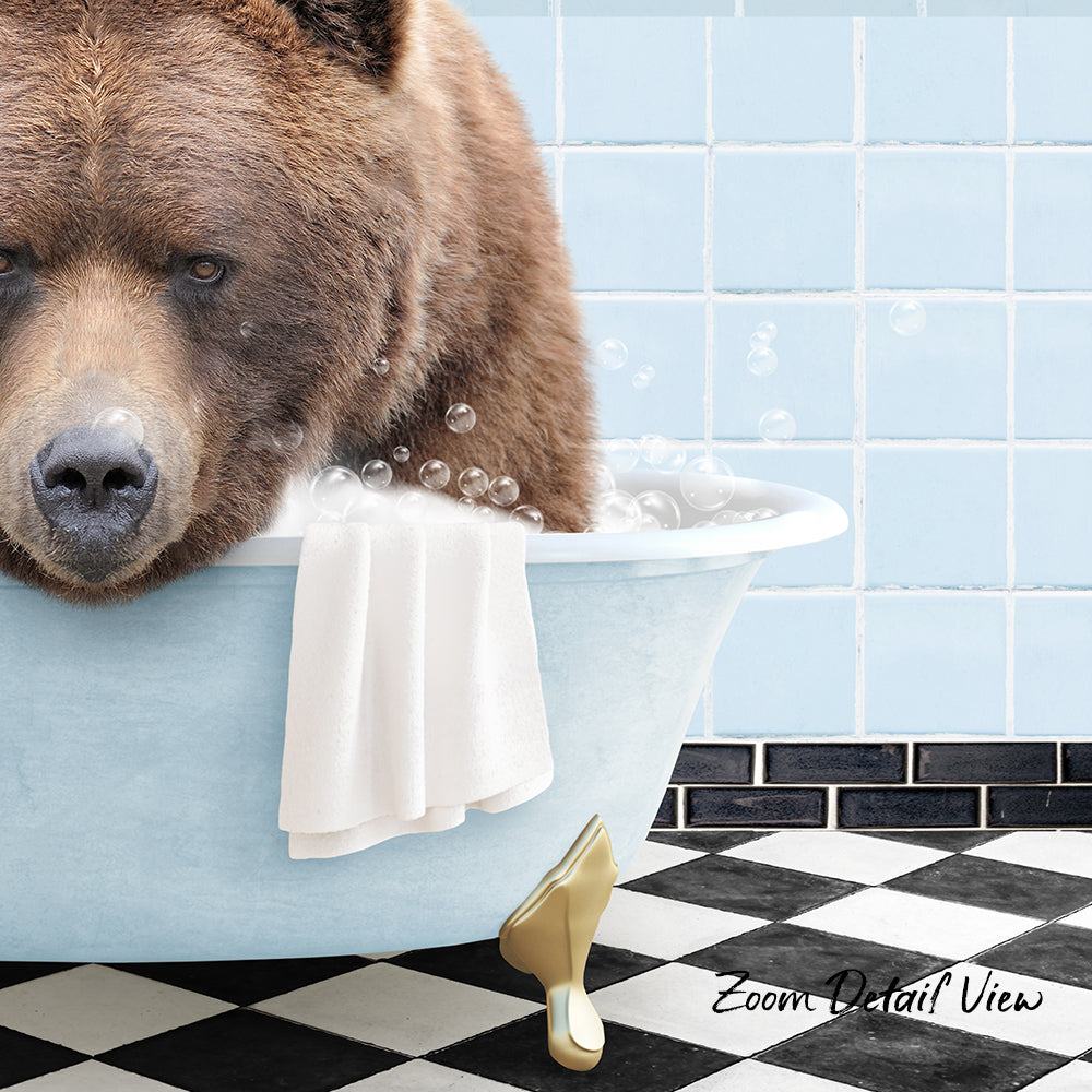 A large brown bear is sitting in a bathtub filled with bubbles, with a towel and a gold object nearby.